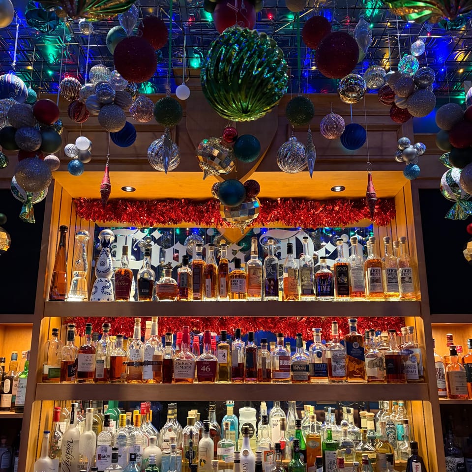 A festive bar at The Noble Lion, adorned with Christmas ornaments and shelves of liquor bottles.